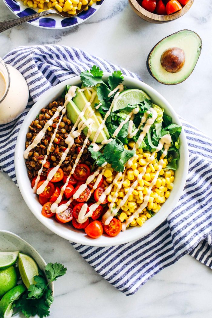 Easy Lentil Taco Salads- seasoned lentils are served on a bed of crisp romaine lettuce with juice tomatoes, sweet corn and buttery avocado. Topped with a creamy cashew salsa dressing, this salad is sure to be a new favorite! (vegan, gluten-free + grain-free with nut-free option)