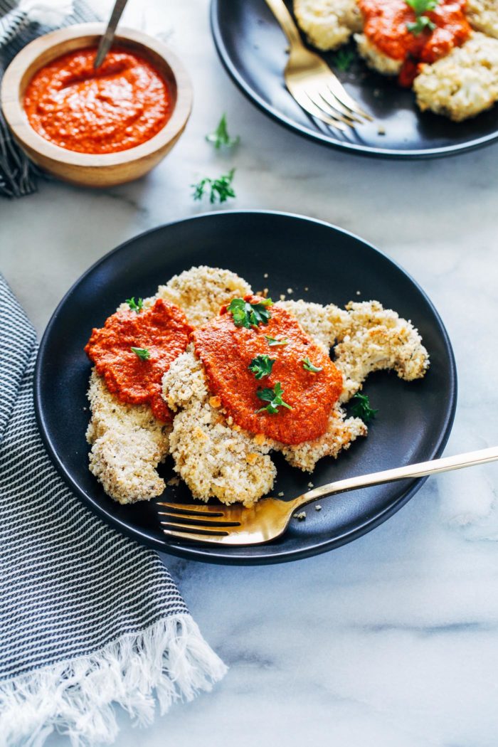 Herb Crusted Cauliflower Steaks with Romesco Sauce- thick cauliflower steaks are coated with crispy panko breadcrumbs and fresh herbs, and served with a garlicky red pepper sauce. 