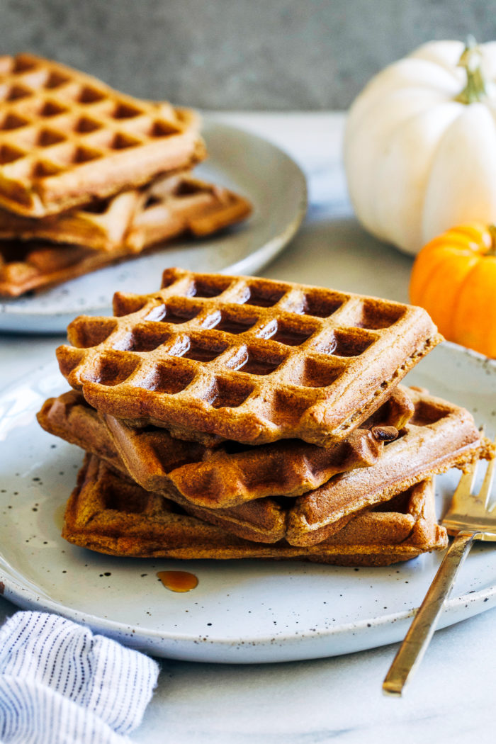 Whole Grain Pumpkin Spice Waffles- made in just one bowl, these healthy pumpkin waffles are deliciously light and fluffy. They can easily be made gluten-free and vegan too! #healthyeating #cleaneating #pumpkinrecipes #plantbased 