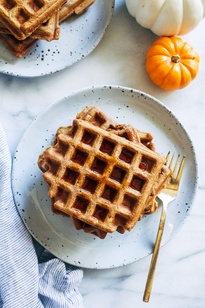 Whole Grain Pumpkin Spice Waffles- made in just one bowl, these healthy pumpkin waffles are deliciously light and fluffy. They can easily be made gluten-free and vegan too! #healthyeating #cleaneating #pumpkinrecipes #plantbased 