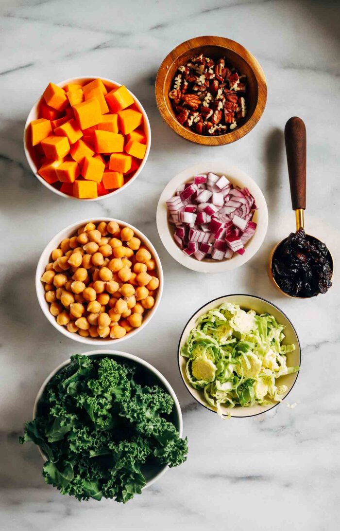 Warm Kale Salad with Maple-Dijon Dressing- A colorful combination of roasted brussels sprouts, red onion, butternut squash and chickpeas served over a bed of kale with toasted pecans and tart dried cranberries. Packed with flavor and texture, this warm salad is sure to leave you craving more!