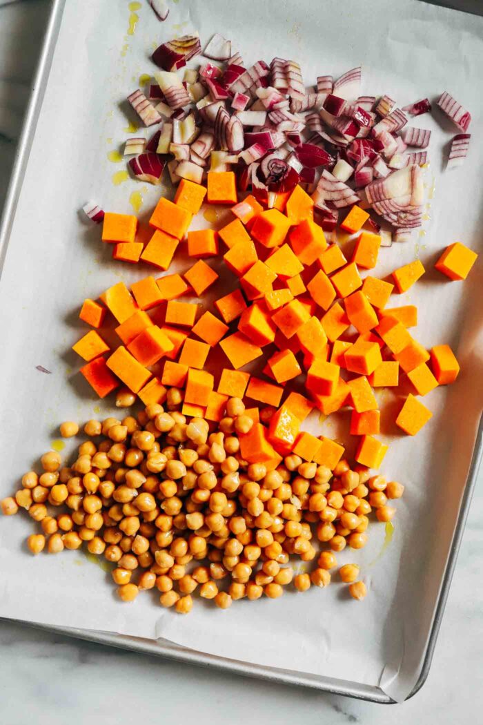 Warm Kale Salad with Maple-Dijon Dressing- A colorful combination of roasted brussels sprouts, red onion, butternut squash and chickpeas served over a bed of kale with toasted pecans and tart dried cranberries. Packed with flavor and texture, this warm salad is sure to leave you craving more!